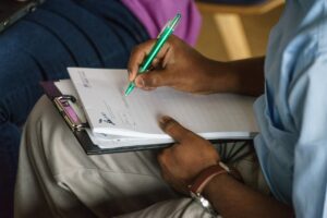 A person is writing on paper that is on their lap