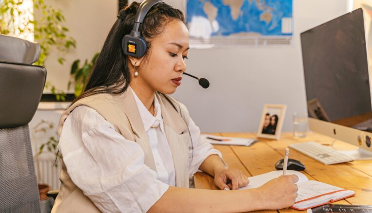 Woman with a headset on writing on a piece of paper